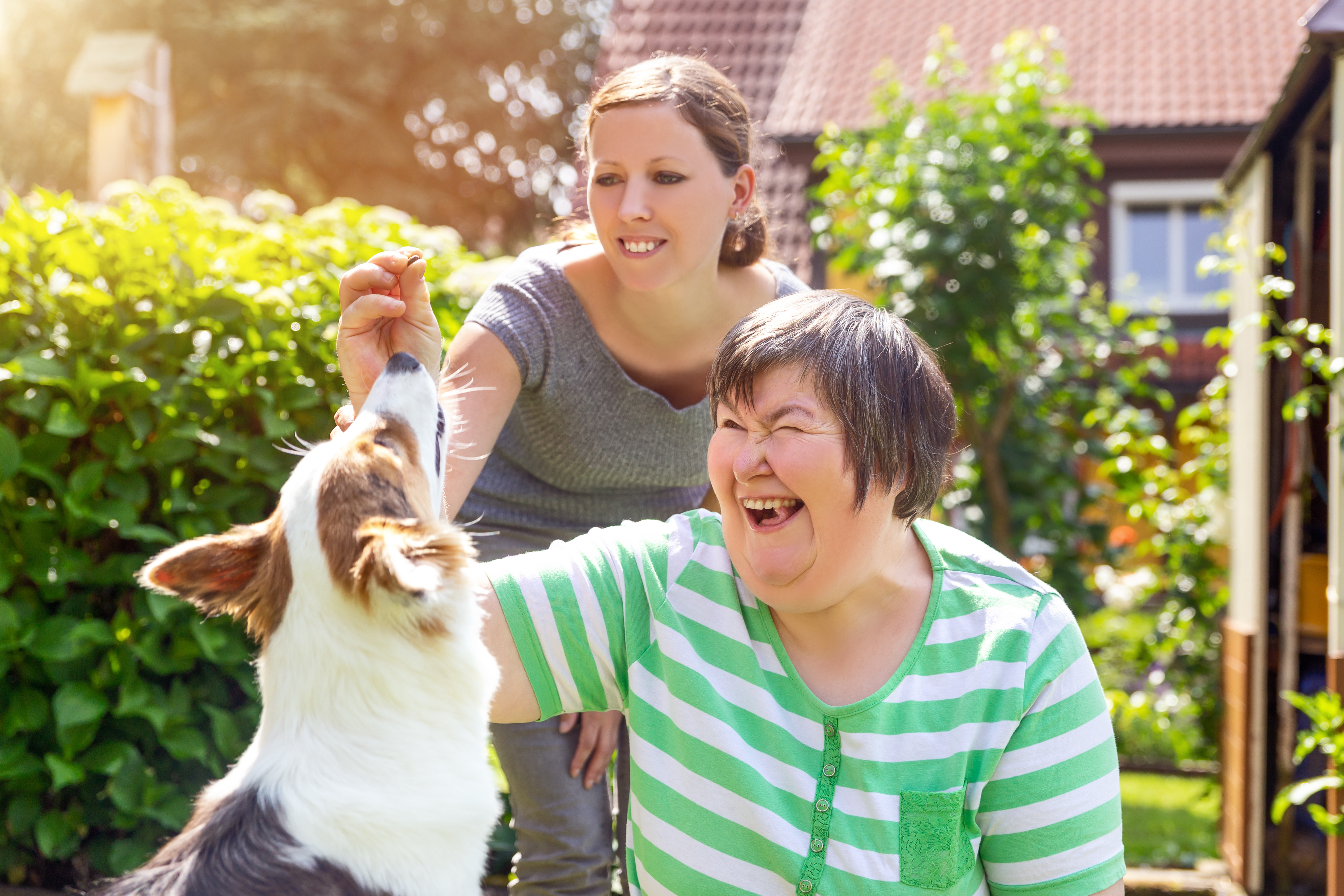 Older woman and female care taker playing with dog
