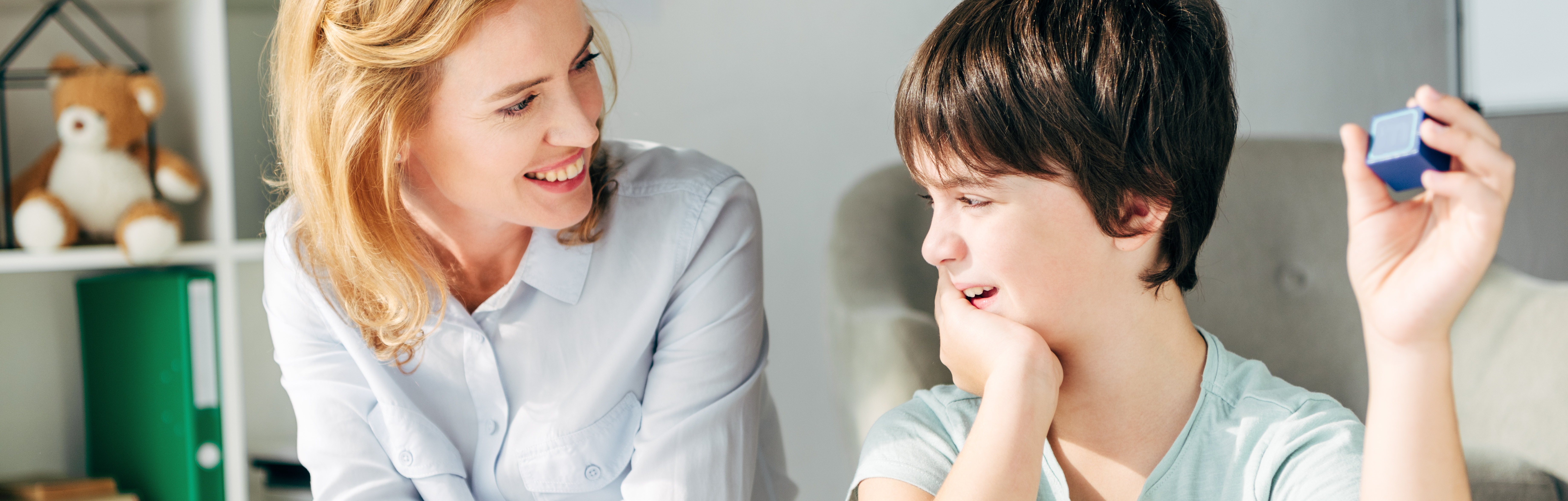 Woman and boy child sitting next to and smiling at each other