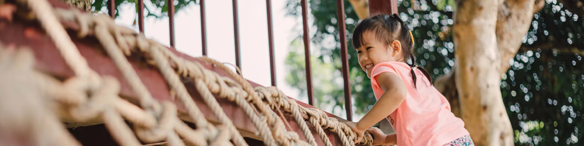 Child playing on rope playground equipment.