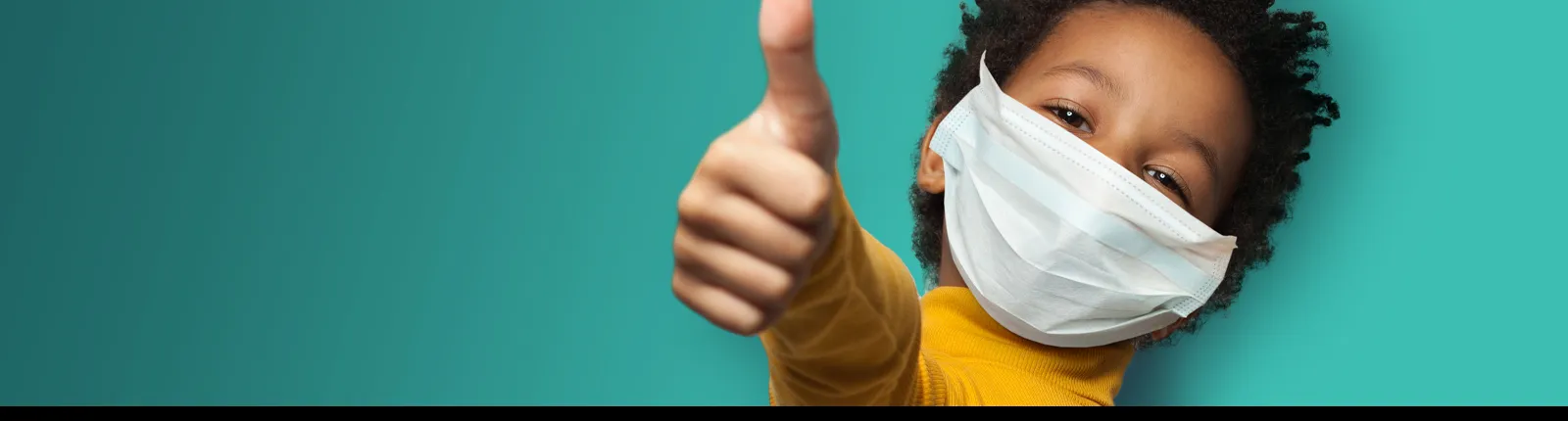 Boy wearing a mask giving a thumbs up