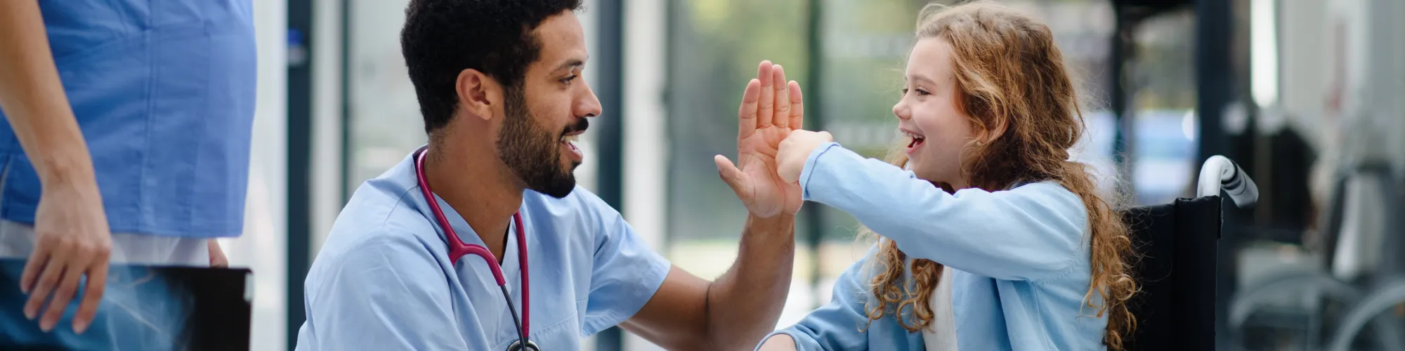 Young friendly doctor interacting with young girl in wheel chair 