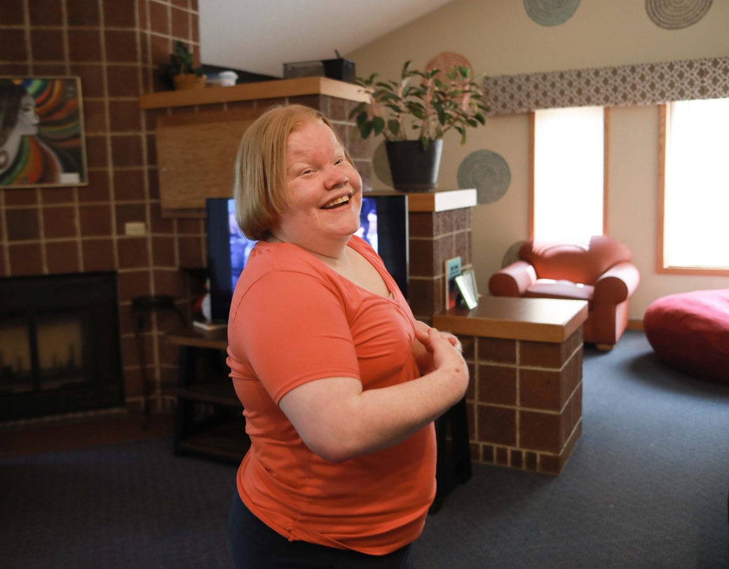 Person smiling, standing in their living room.