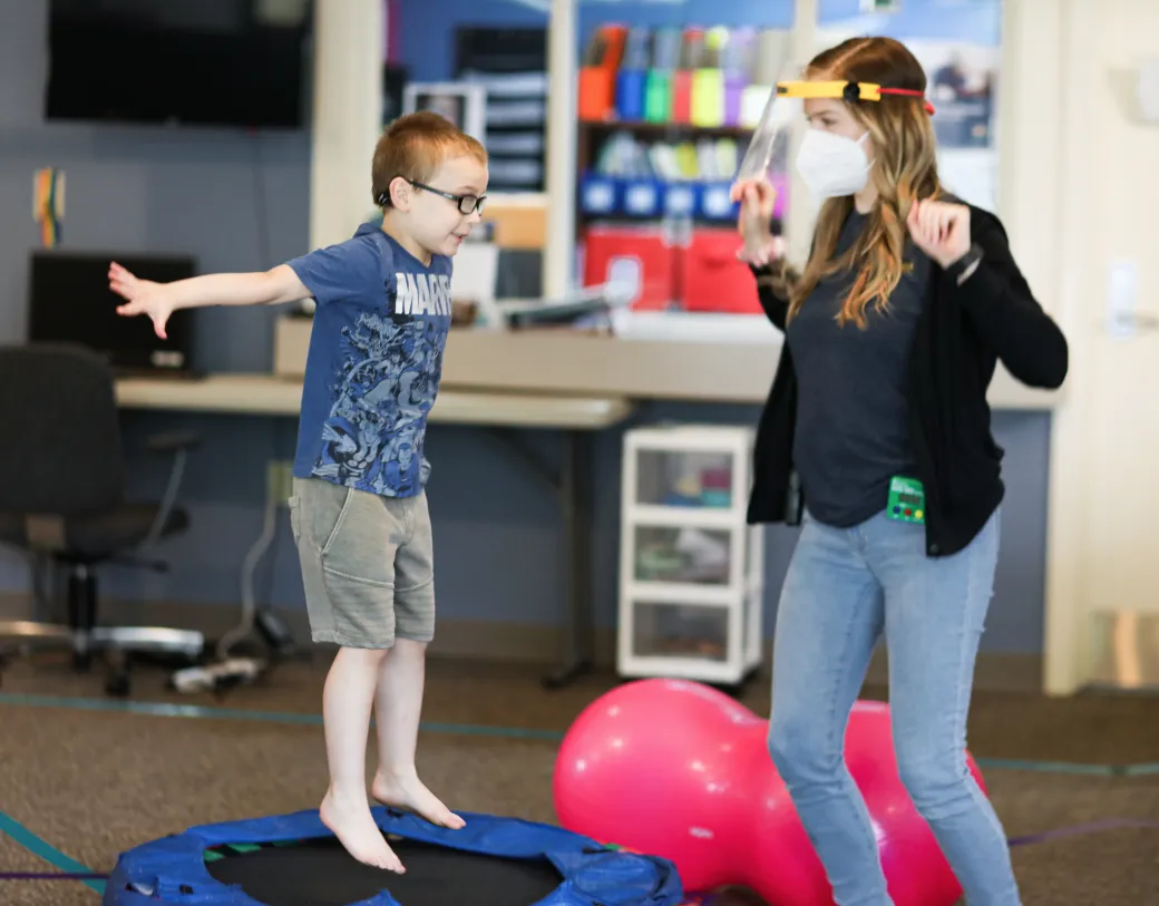 Child excitedly jumping with staff member.