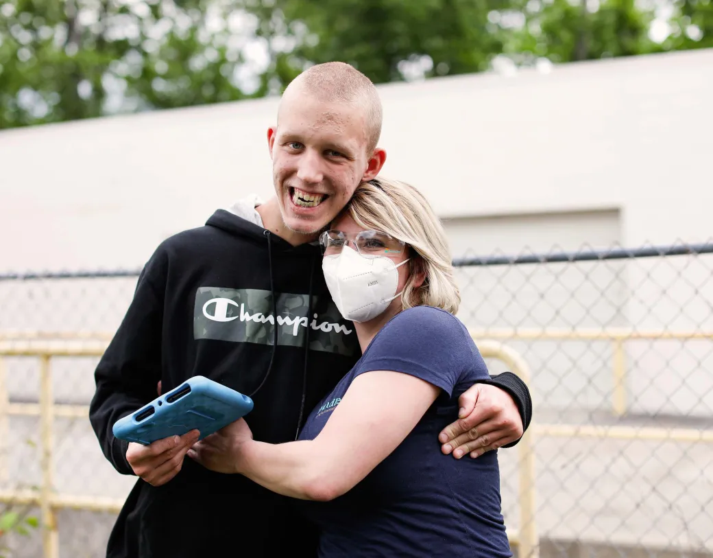 Teenage patient and healthcare provider hugging.