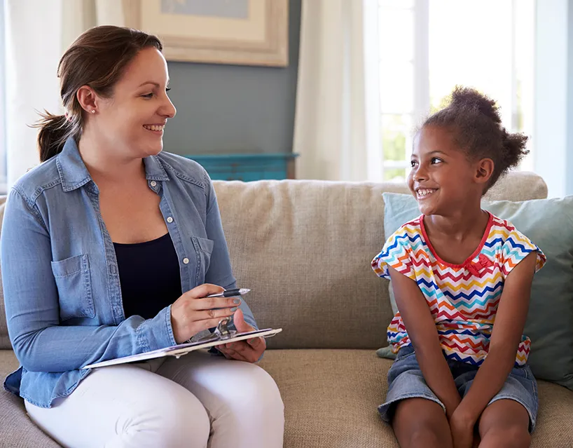 Care coordinator talking with a little girl on a coach