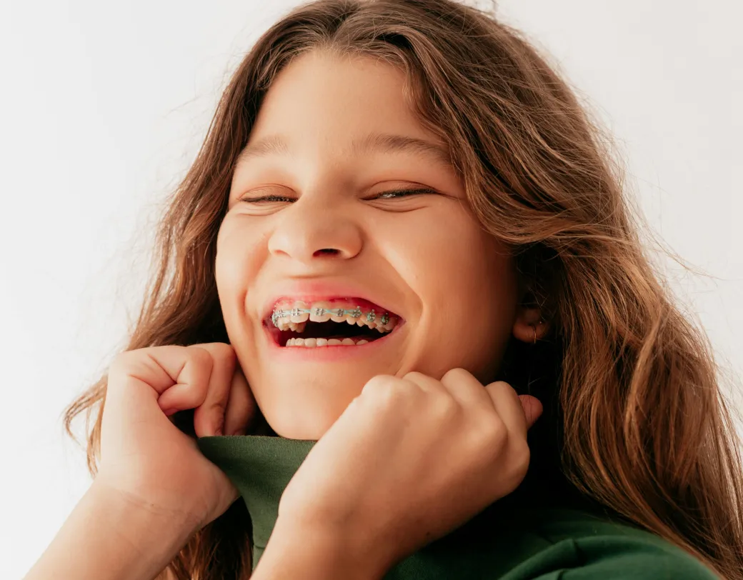 Smiling brown haired girl with braces.