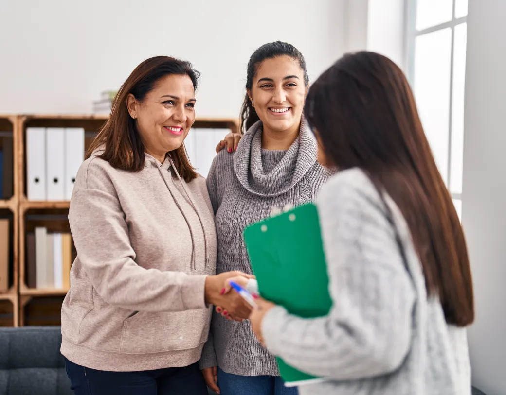 Two women smiling and shaking hands with a Psychiatrist