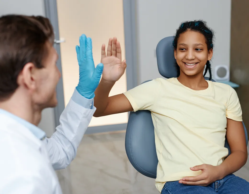 A dentist giving a high five to his patient in an exam chair 