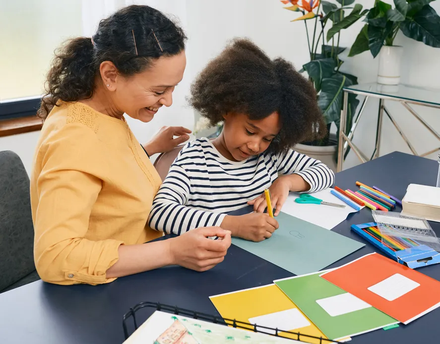 Woman working with child writing in a notebook