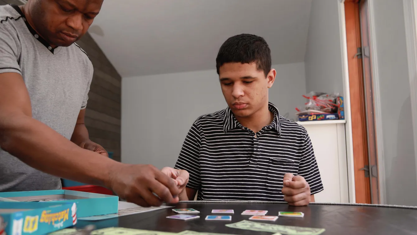 Young adult sitting at table with paper money, healthcare worker standing and hold paper money.