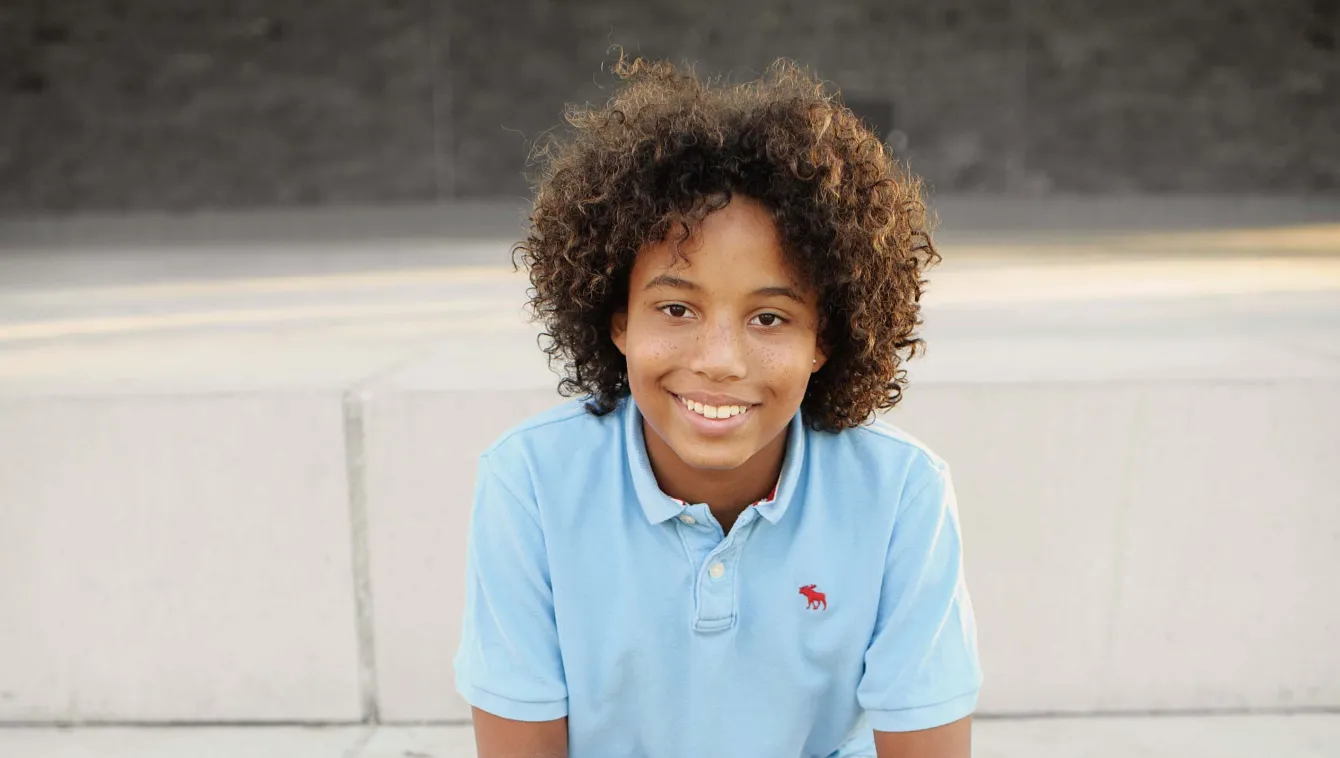 Child sitting on concrete steps, smiling.