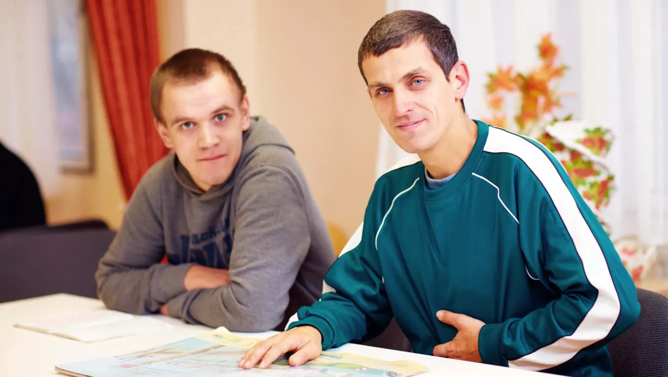 Two adults sitting at a table looking through a magazine.