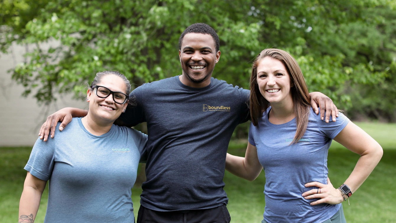 Three Boundless employees posing outside with arms around each other.