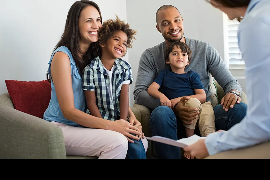 A happy family sitting on a couch speaking with a counselor