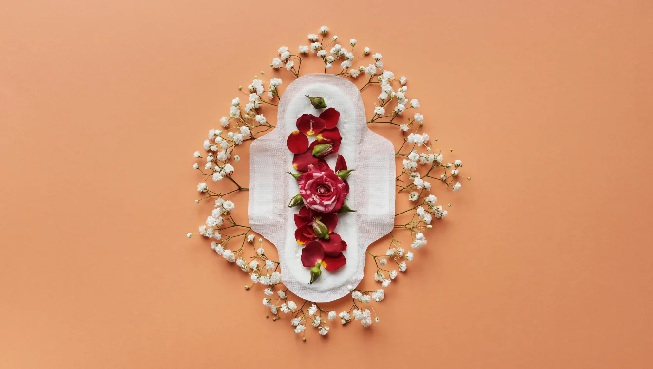 Open pad laid on orange background, covered in rose petals and surrounded by baby's breath.