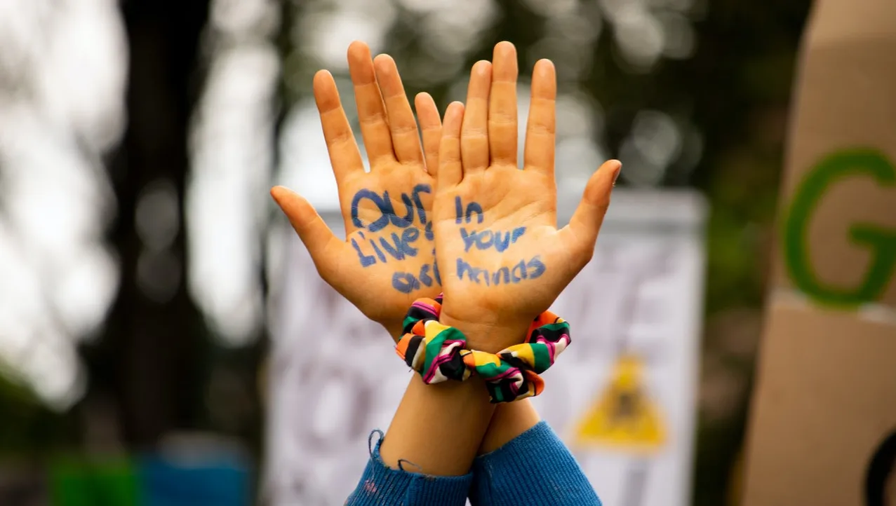 Person raising hands on which is written "Our Lives Are in Your Hands"