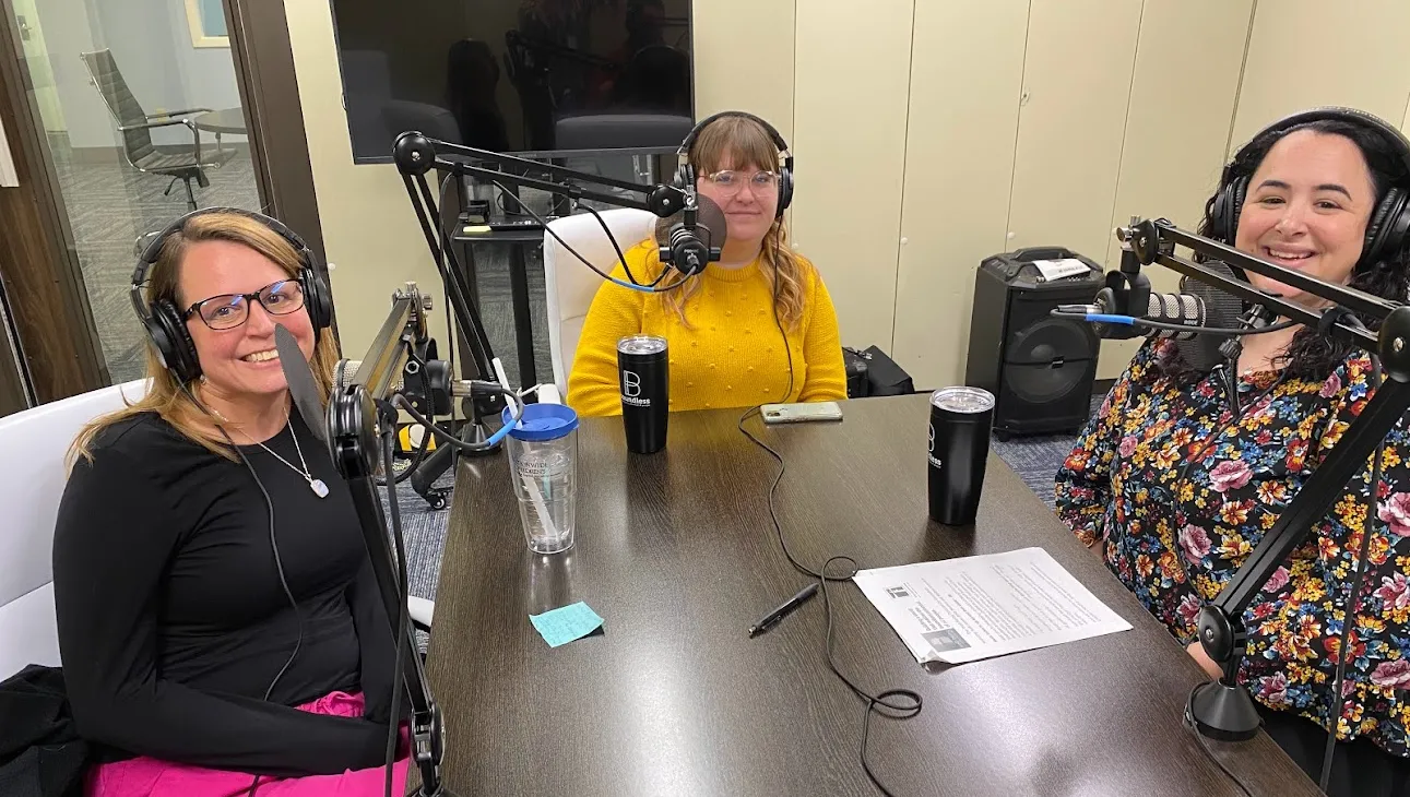 Three women at a table recording a podcast