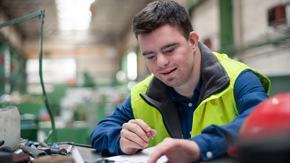 Young man with Down syndrome working in industrial factory