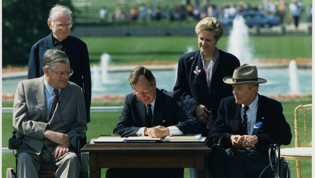 Photo of President George H. W. Bush signing the Americans with Disabilities Act inscribed to Justin Dart, Jr., 1990.