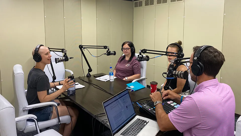 Patti Cain, Sue Hall, Tessa Subler, and Scott Light at a table recording a podcast. 