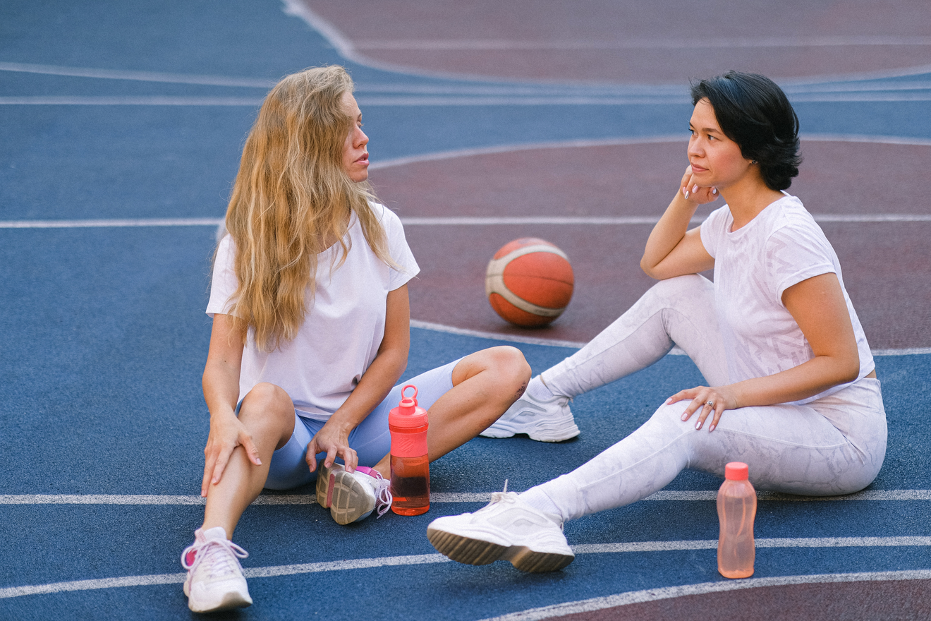 Two Girls Sitting on a basketball court