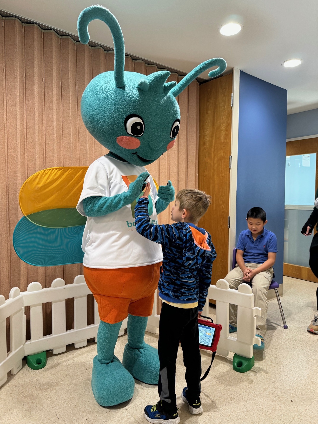 Bubbles mascot giving high fives to boy