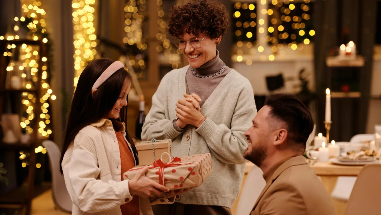 Two adults give a girl a gift for the holiday season