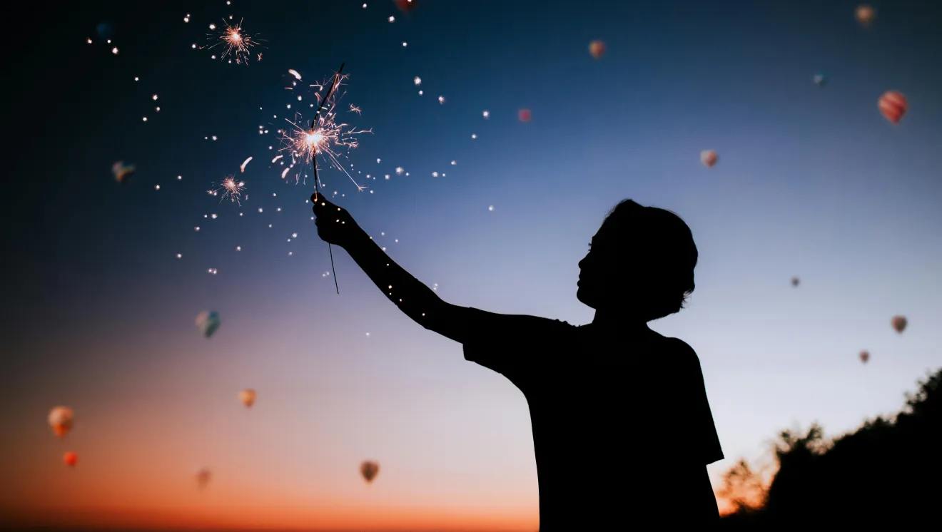 A silhouette of a child holding a sparkler during fireworks