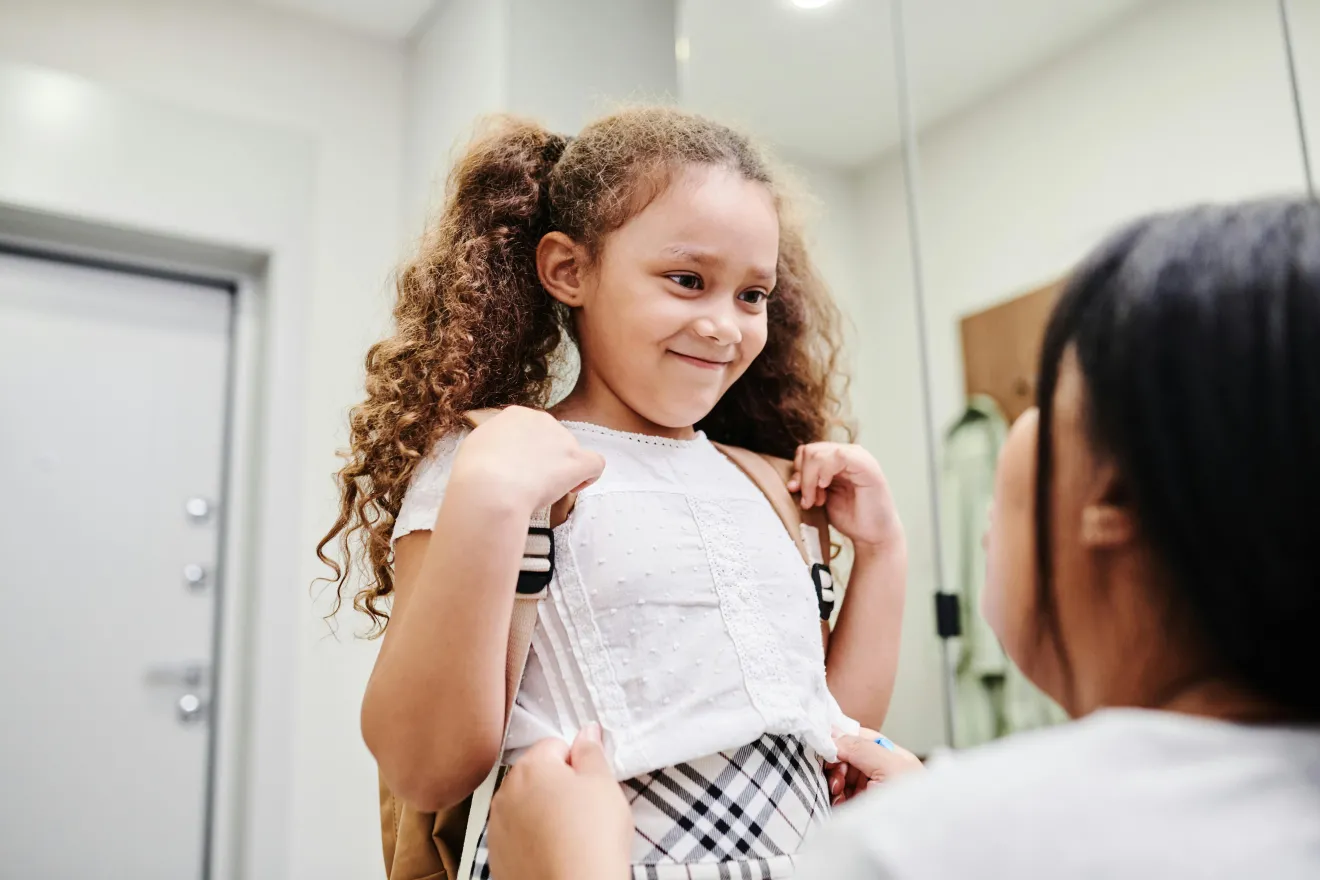 A mom helps a child get ready for school