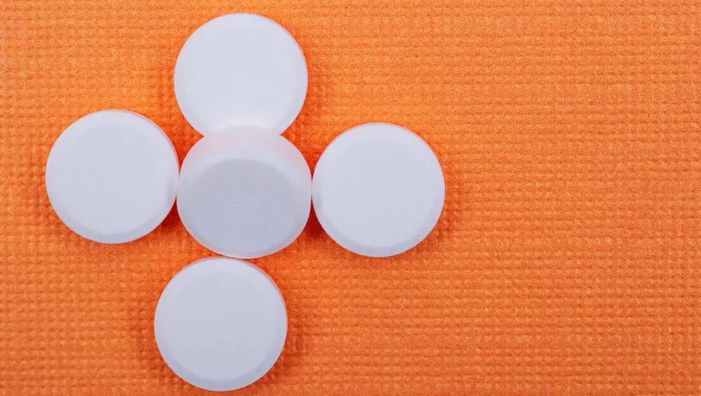 white acetaminophen tablets over orange background