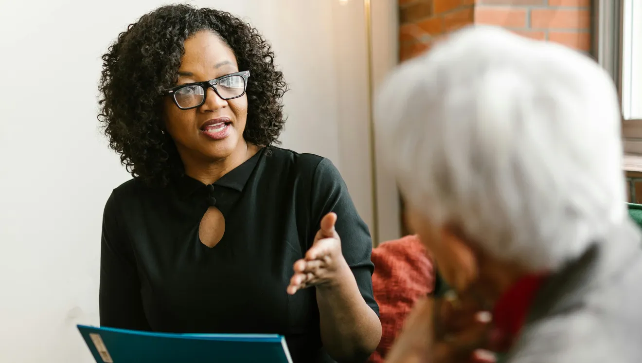 Female social worker engaging in conversation with elderly female client.