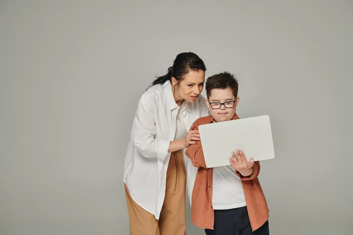 middle aged woman explaining online lesson to child with an intellectual disability