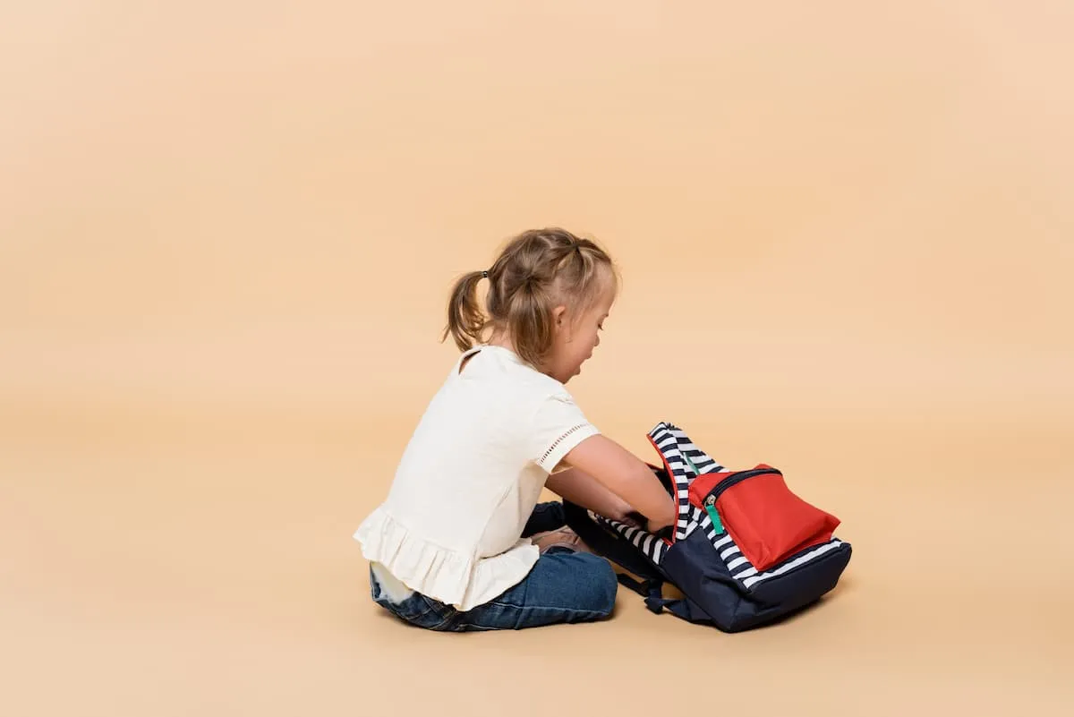 young child with an intellectual disability looking through her backpack