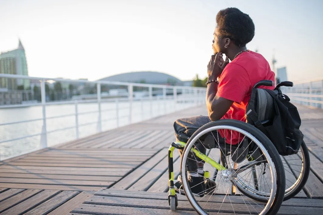 A person in a wheelchair looks into the distance thoughtfully