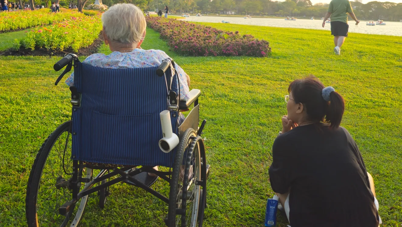 Elderly person in a wheelchair and a younger caregiver