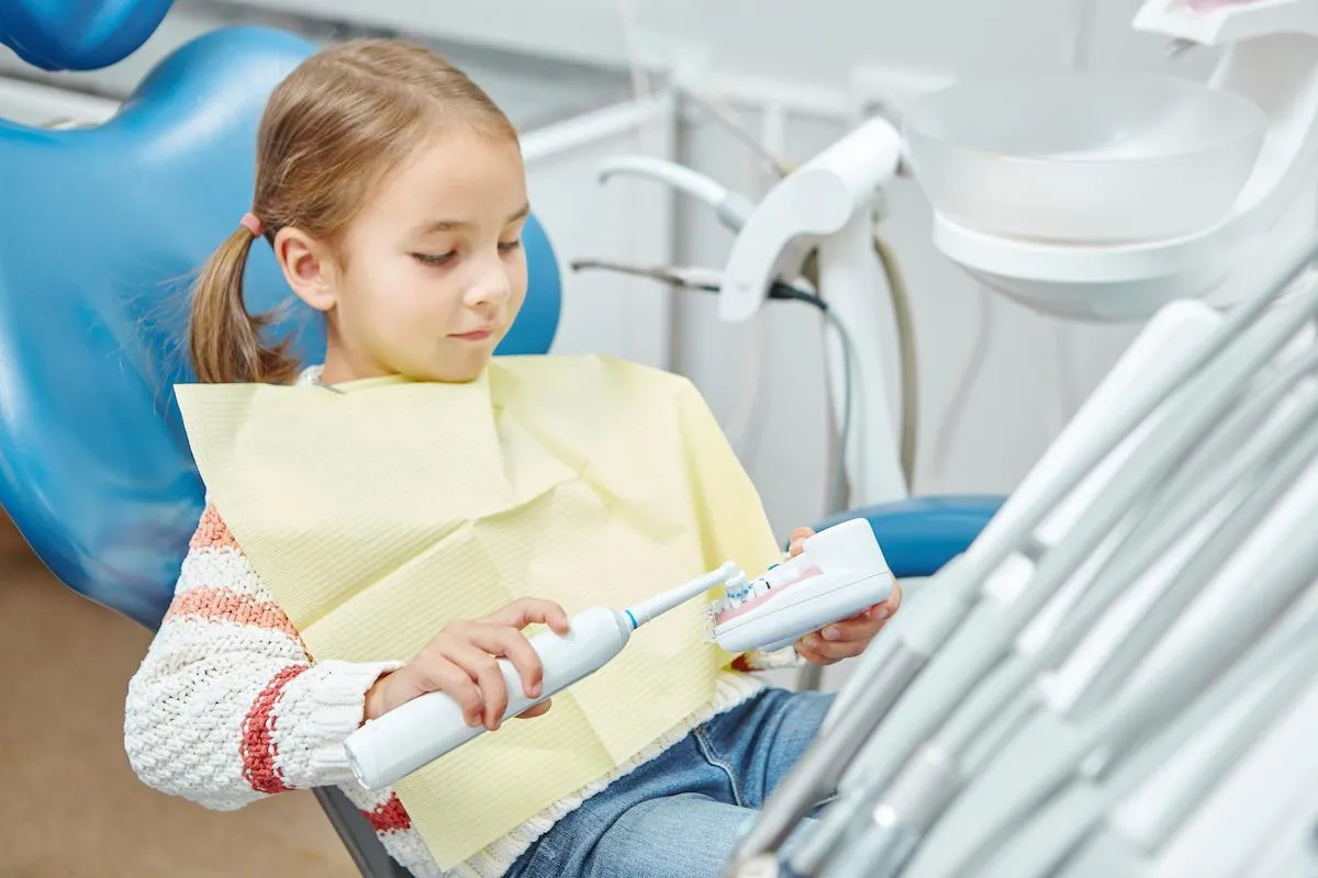child sitting in dental chair exploring dental tools