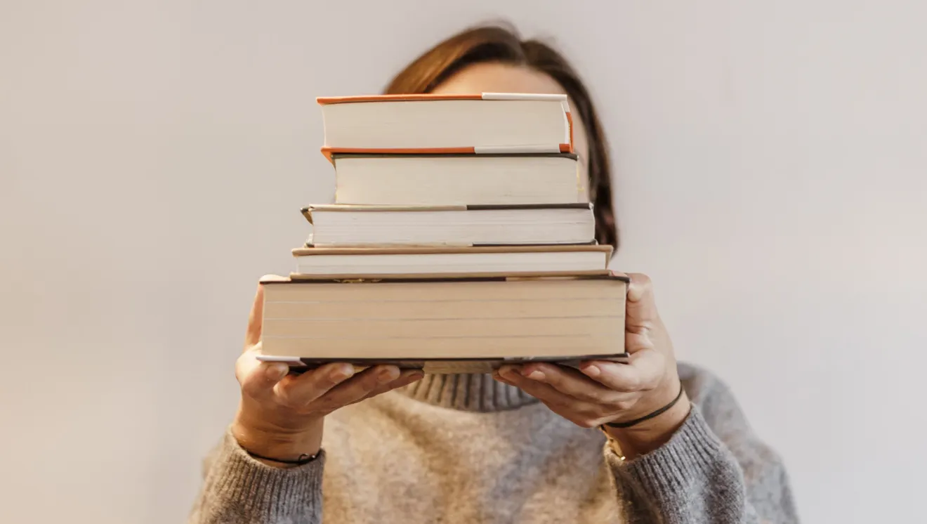 girl holding a stack of books